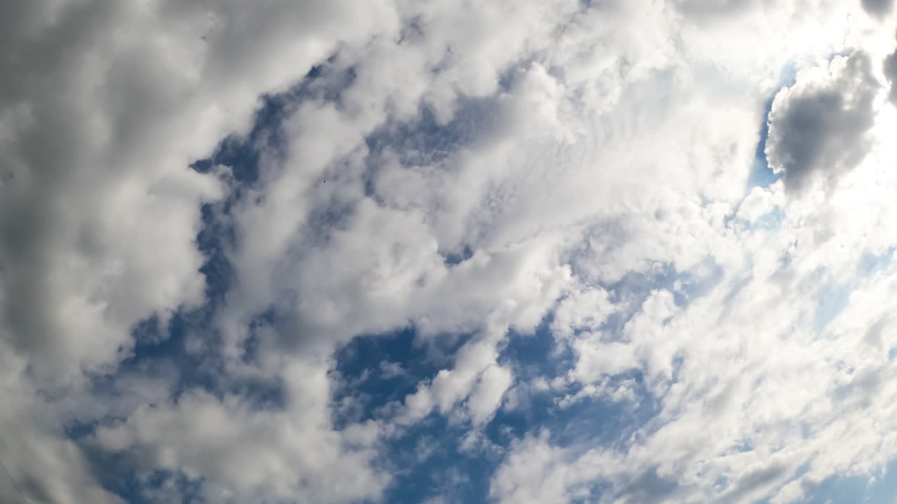 White clouds accumulating in the atmosphere. Sun lighting the soft cloudscape from top. Low angle view. Timelapse.