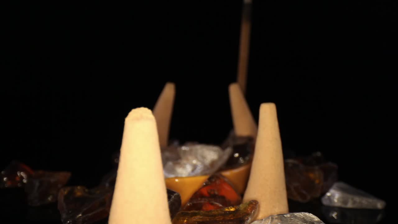 alejándose de varios conos de incienso apagados en un jardín de rocas decorativas, lejos de un palo no encendido