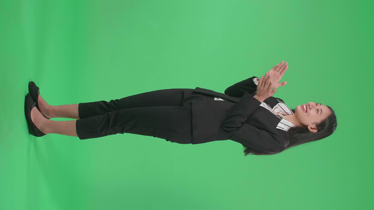 Full Body Side View Of A Smiling Asian Business Woman Clapping Her Hands In The Green Screen Studio