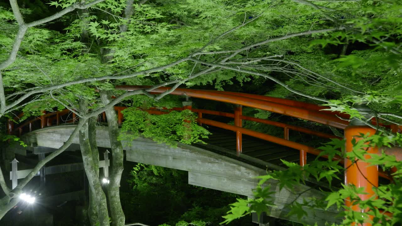 Famous red bridge at Ikaho Onsen inside forest illuminated at night