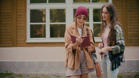 woman sharing book with tourist friend near building