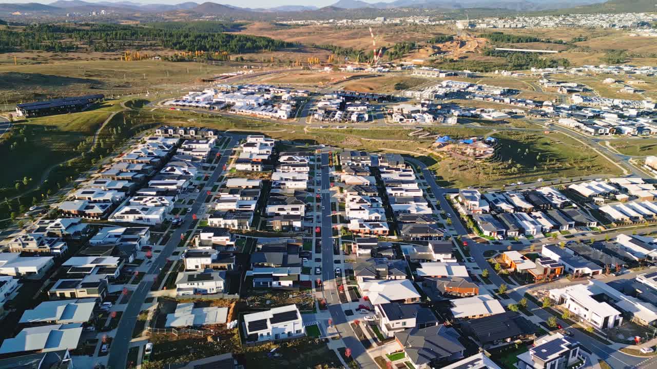 Drone captures a Canberra suburb from above showing completed homes next to open fields awaiting future expansion.