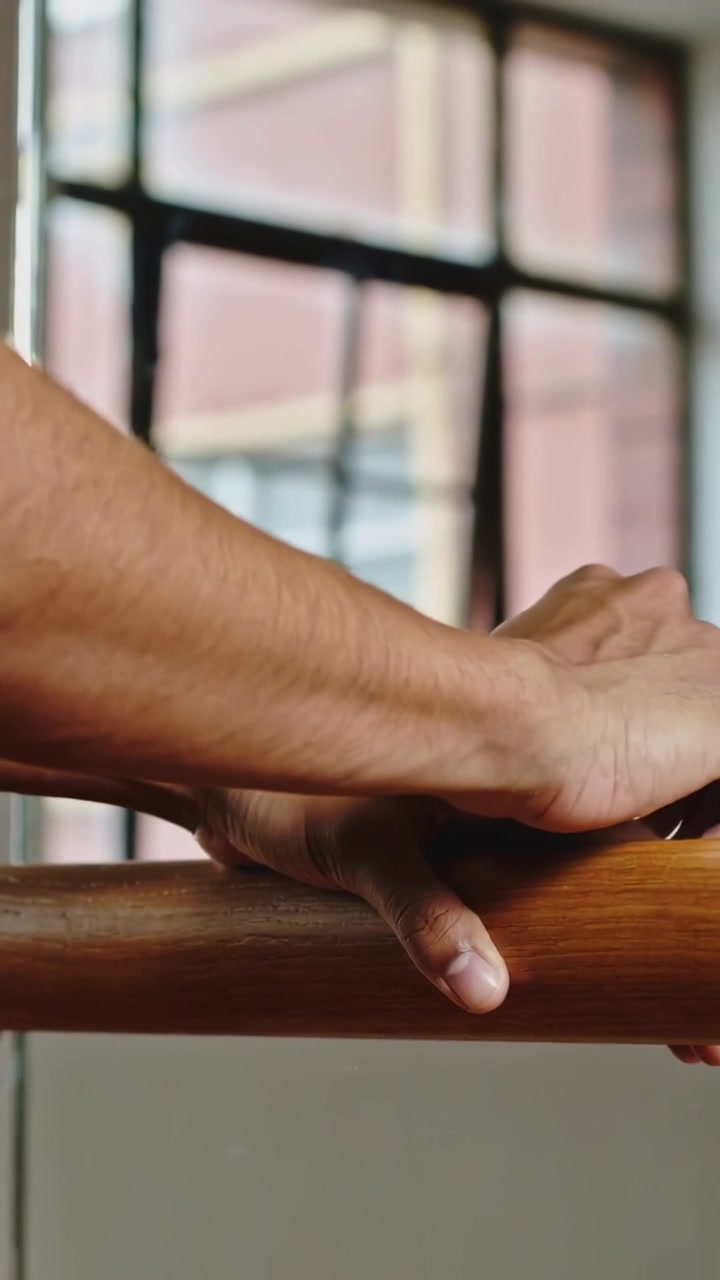 Vertical video: Resting bare arm-hand leading curling or gripping or sliding right on barre studio w