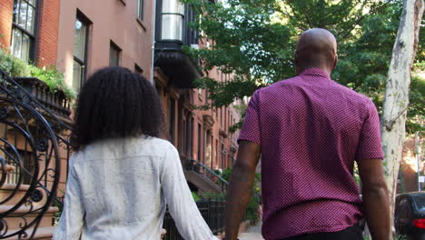 rear view of couple walking along urban street in new york city