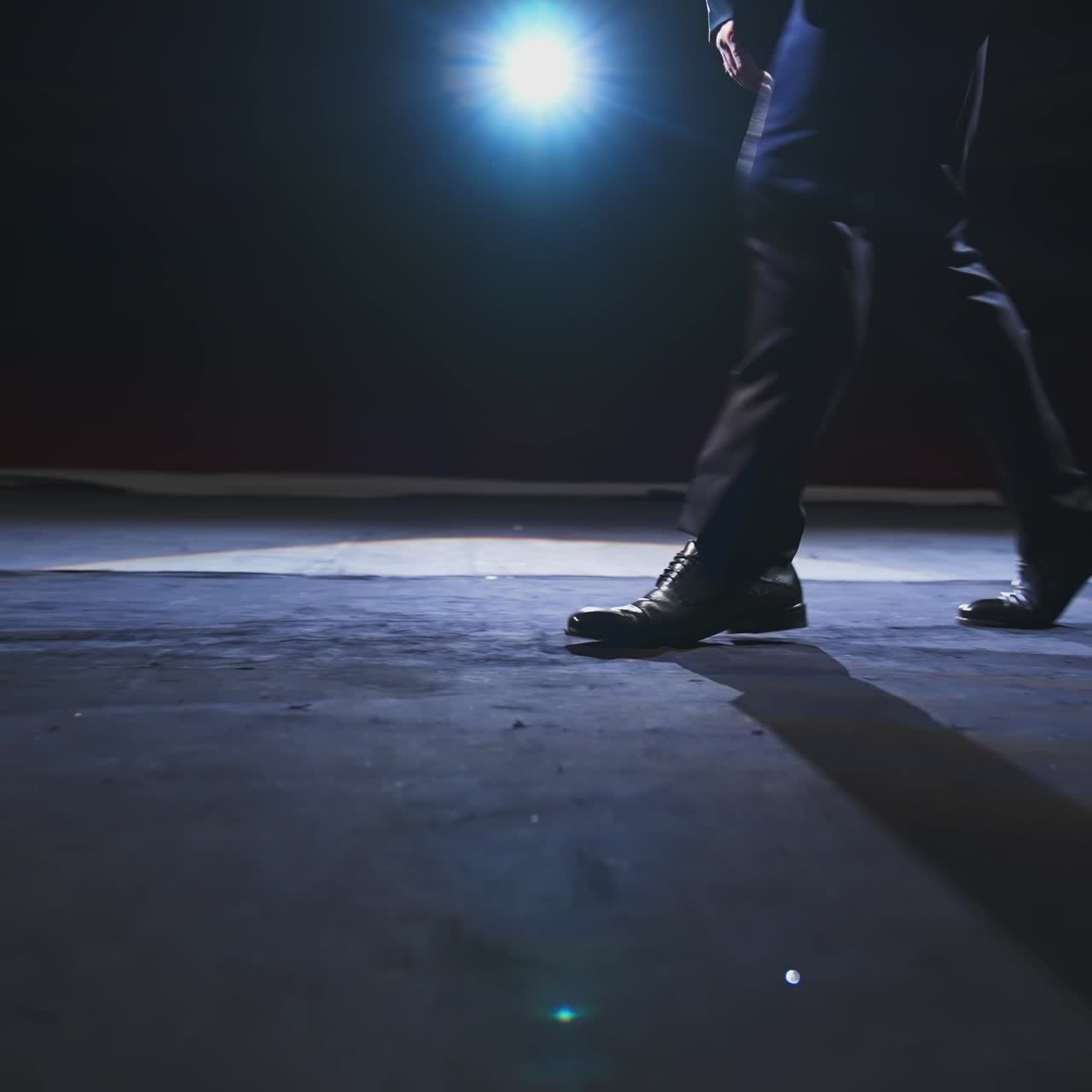 Male's legs on stage. Man actor in trousers and black shoes dancing on stage. Close-up.