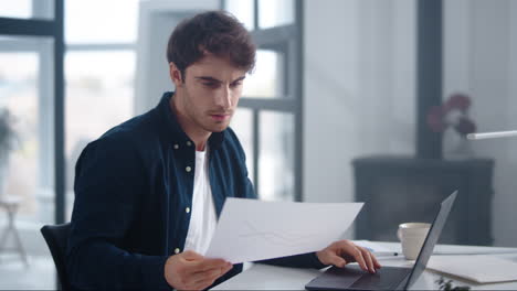 Focused-businessman-reading-document-indoor.-Serious-guy-looking-papers-at-work