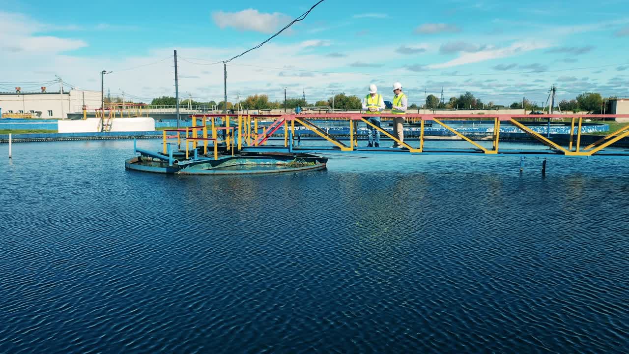 두 명의 폐수 운영자가 정제기를 검사하는 공중 사진