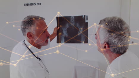 animation of network of connections over caucasian male doctors reading x-ray scan