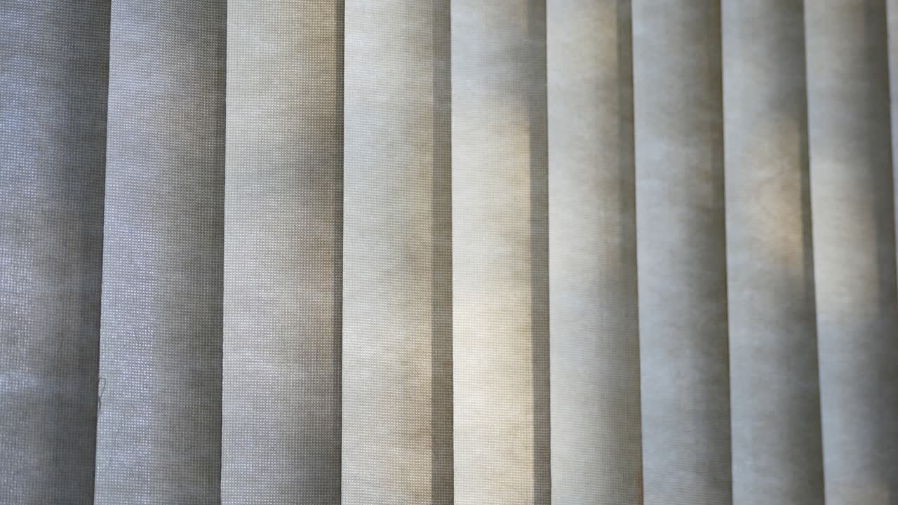 Trees shadows dancing outside on closed fabric vertical home blinds surface