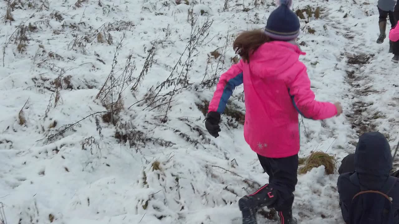 Slow motion family running and sledging in snow field