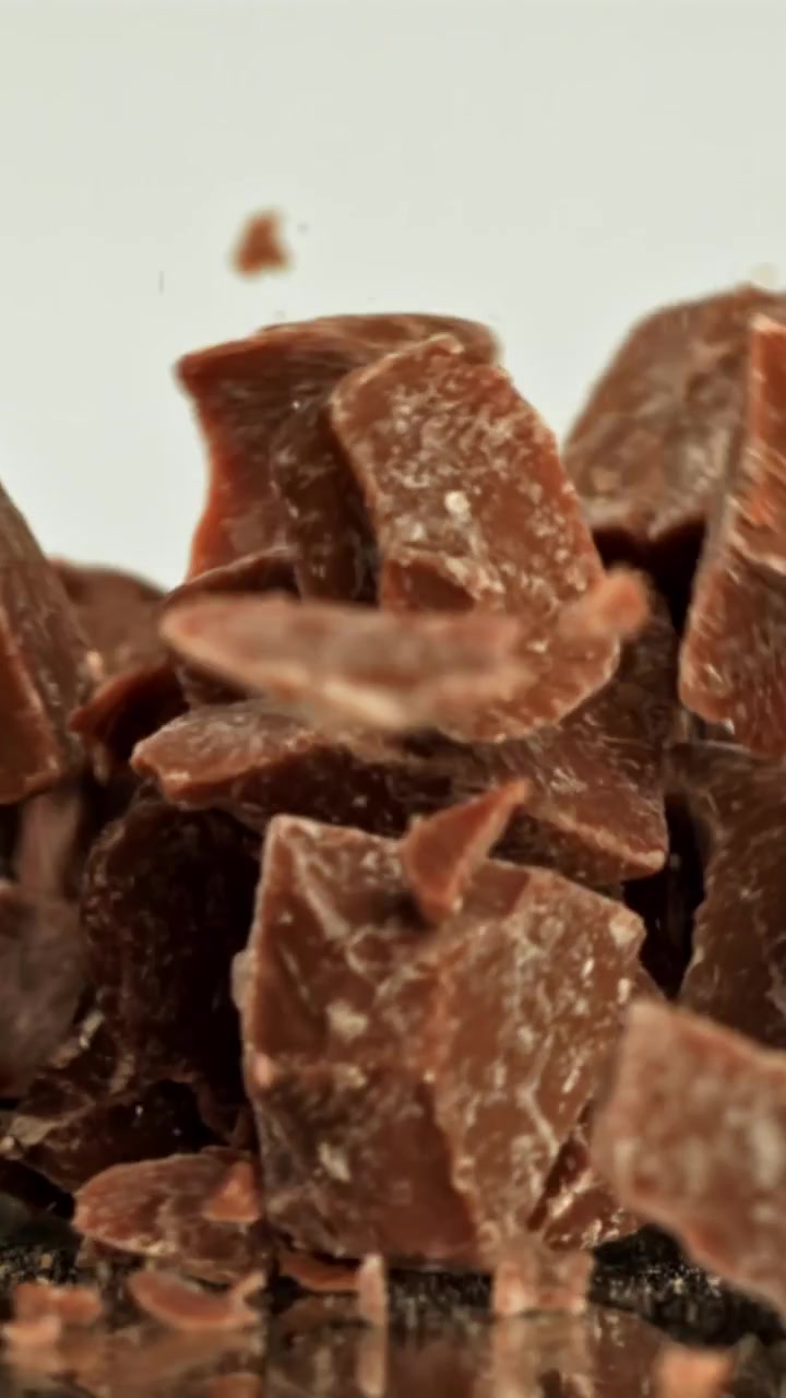 Pezzi di cioccolato che cadono al rallentatore su sfondo bianco