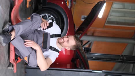 mechanic taking a break or checking his phone while working on a car in a garage