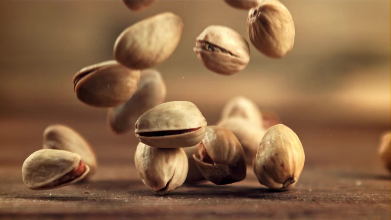 Deliziosi pistacchi che cadono al rallentatore su un tavolo di legno