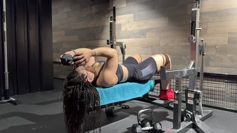 a woman performs dumbbell triceps extensions on a bench in slow motion, arms extending and bending repeatedly