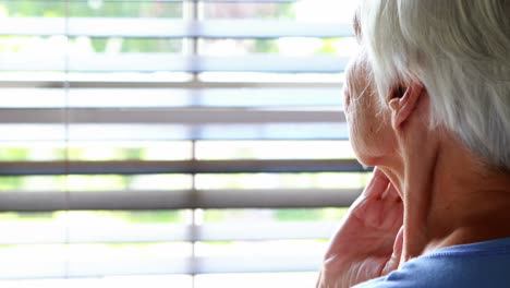 Senior-woman-looking-out-from-window