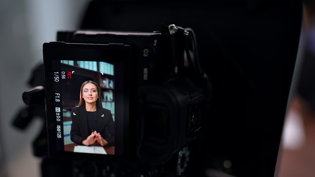 Display of professional camera with a female speaker. Woman shows face exercises for her blog. Close up.