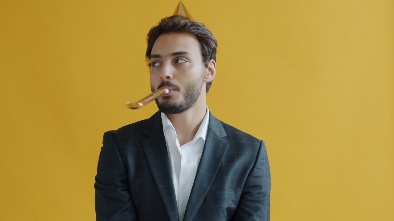 Man in a suit blowing a party horn