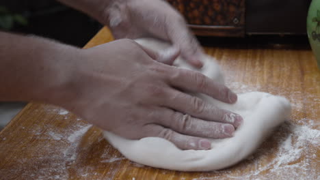 close up on hands forming the pizza dough