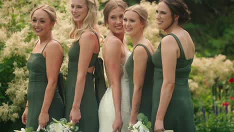 bride and bridesmaids pose for a group photo in a flower garden