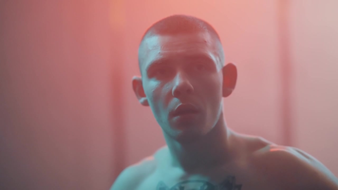 Giovane uomo tatuato dallo sguardo intenso che guarda in alto sotto un'illuminazione al neon suggestiva
