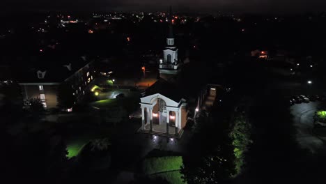 aerial approaching shot of church in american town at night. lighting facade of american cathedral in lynchburg, virginia.