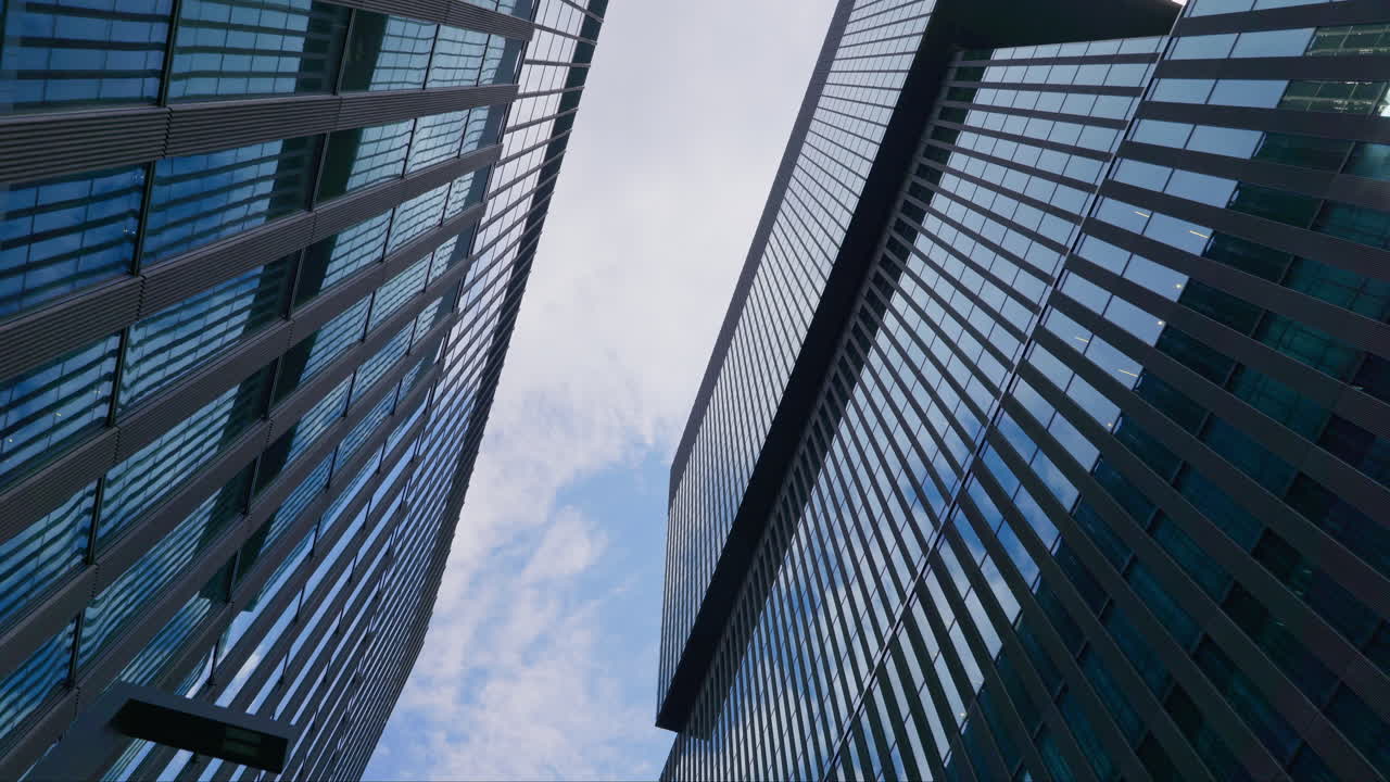 Vista ascendente entre edificios de oficinas modernos y altos, exteriores de ventanas reflectantes