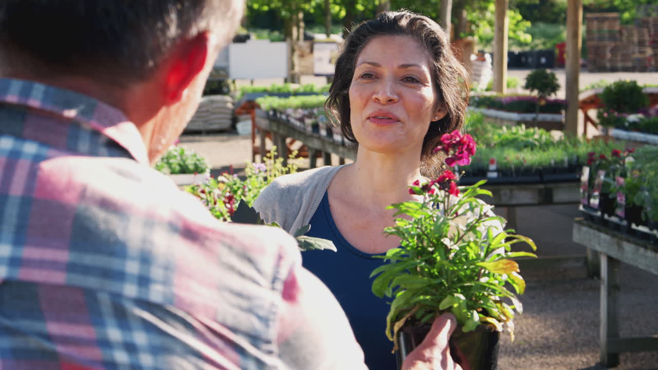 mujer madura cliente compra plantas de asistente de ventas masculino en el centro de jardinería