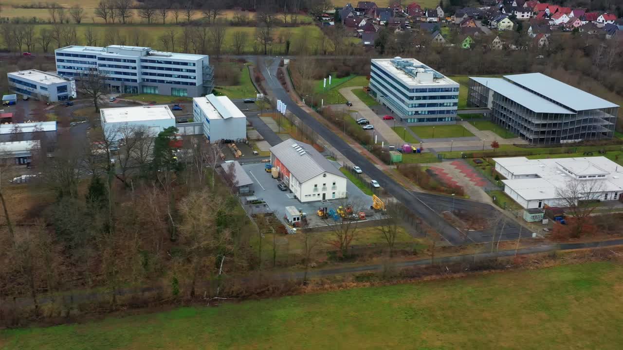 Luftaufnahme eines kleinen Gewerbeparks mit Verwaltungsgebäuden und einem leeren Parkhaus