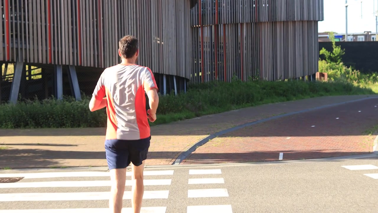 Male trail runner on sidewalk in the morning. Athlete endurance training run exercise outdoor sports concept. Steady shot of person in motion