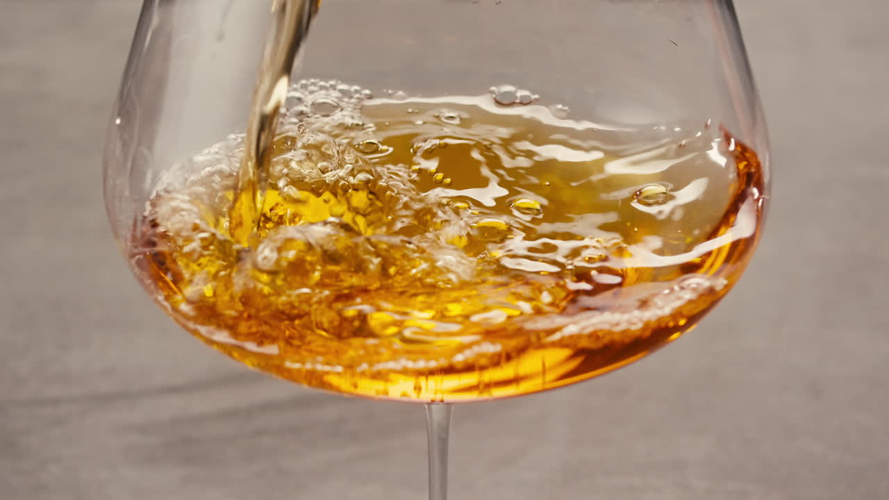 Orange or white wine bottle and glass against a sunset in a peaceful vineyard, pouring of ecological natural wine.