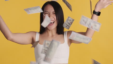 asian woman looking happy while throwing money up.