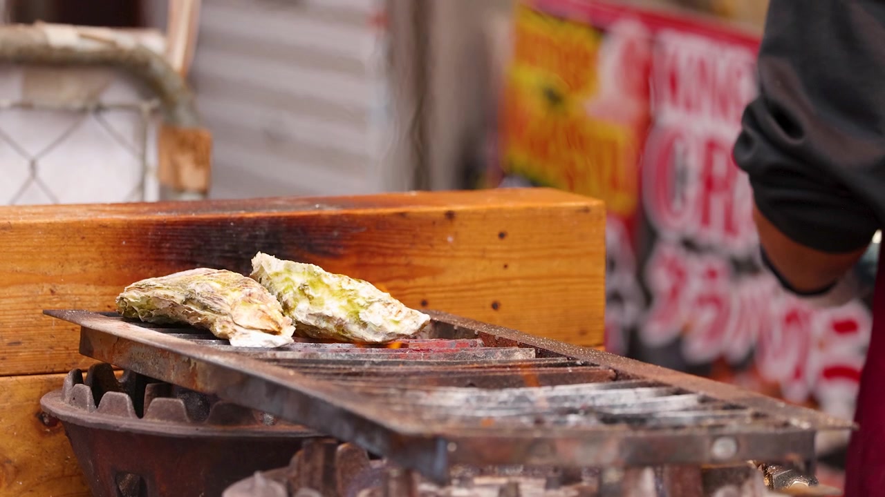Ostriche fresche alla griglia su fiamma viva in una bancarella di street food.