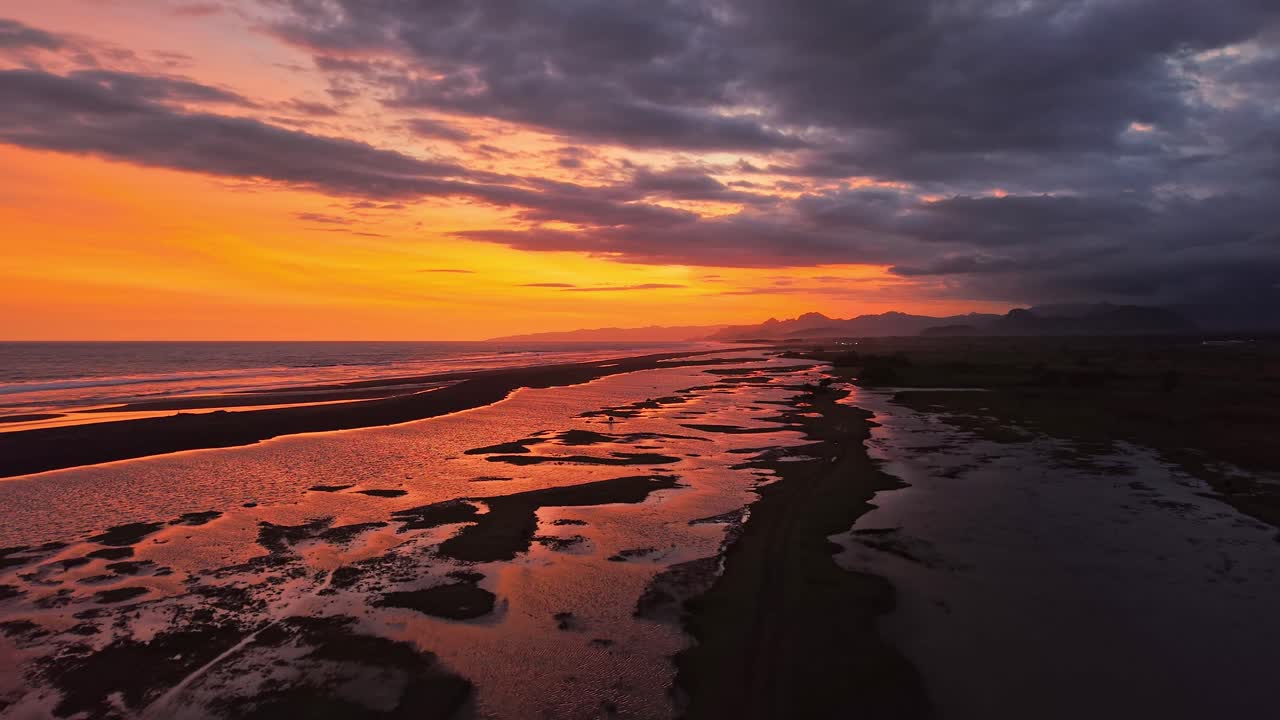 Dramatischer Sonnenuntergang über dem Strand mit glühend orangefarbenem Himmel und ruhigem Wasser, malerische Küstenlinie, ruhiger Abend, Naturhintergrund.