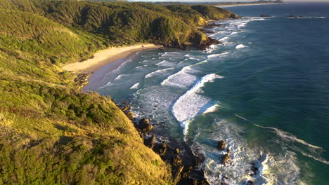 rising drone shot of rocky coasting and crashing waves at broken head beach near byron bay