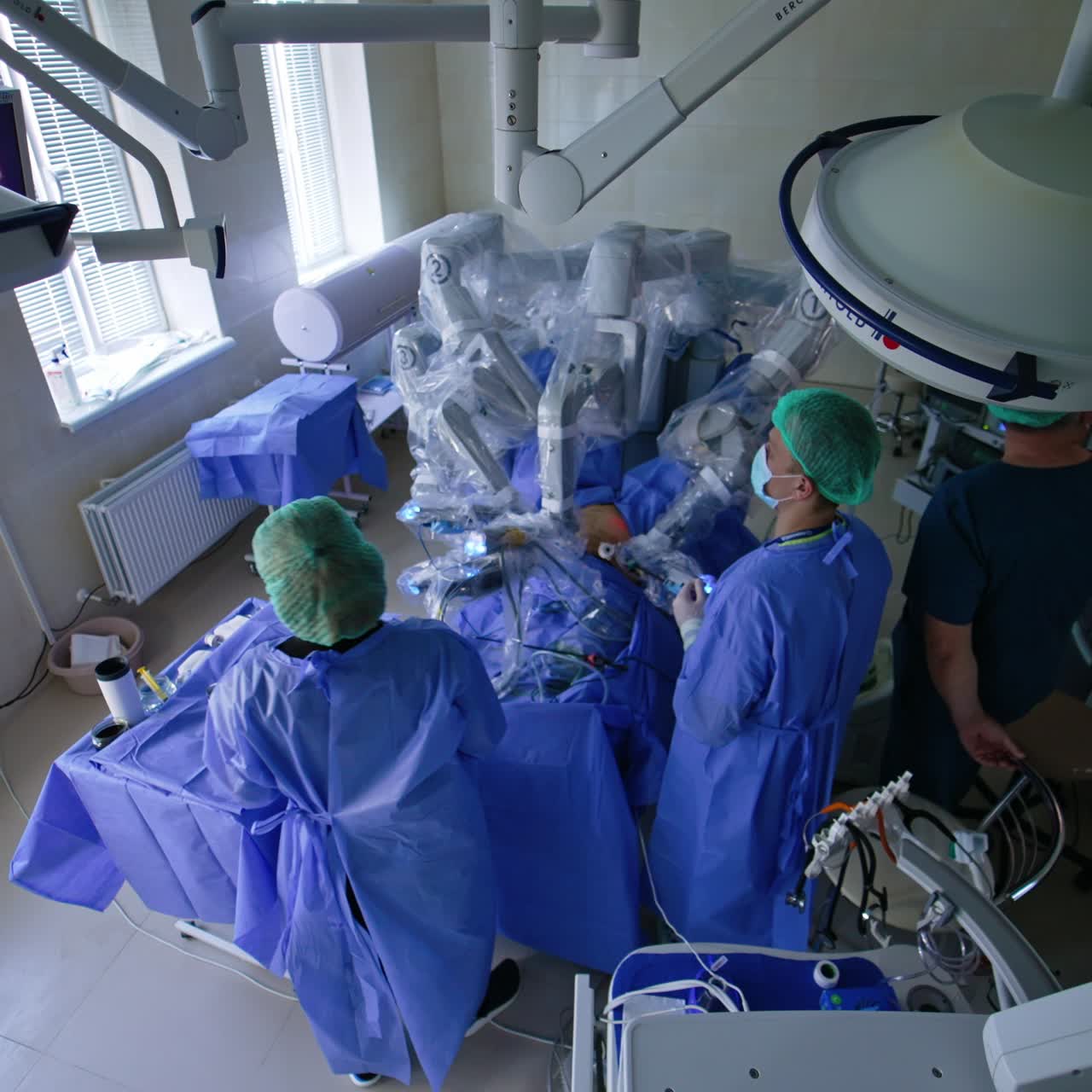Laparoscopic operation conducted by innovative Da Vinci robot. Male surgeons watch the process on the monitor. View from top