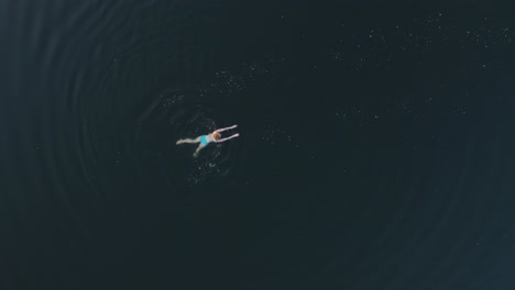 drone shot into the lake where the girl is swimming