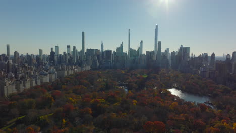 Softball-fields-on-The-Great-Lawn-among-colourful-autumn-trees-in-Central-Park.-Tilt-up-reveal-modern-midtown-skyscrapers.-Manhattan,-New-York-City,-USA