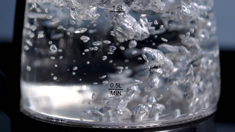 rapid boiling water in a clear glass kettle, slow motion, close up