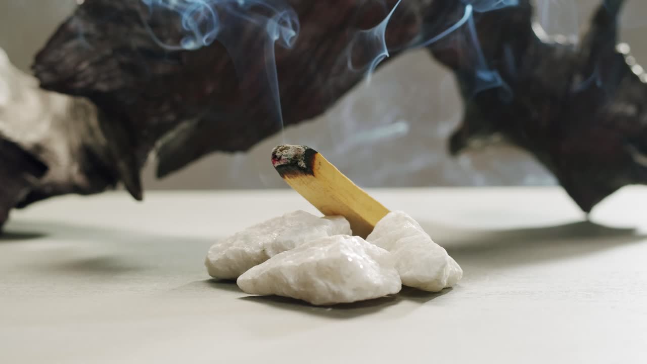 Person holding Palo Santo wood stick in hand, aromatic Palo Santo burning on black background, smoke spreading around, slow motion video clip, high quality 4k close up footage. High quality 4k footage