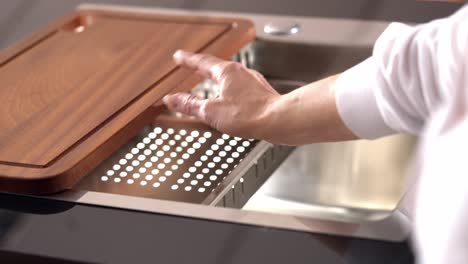 Kitchen-worktop-with-wood-cut-out-and-metal-tap-in-steel-kitchen