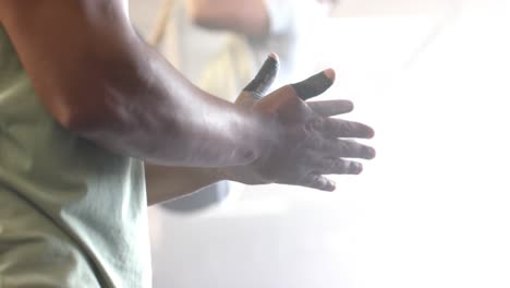 diverse men chalking hands and climbing rope at gym, in slow motion