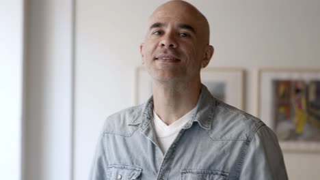 Front-view-of-handsome-serious-bald-man-posing-at-home