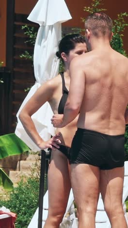 personas sentadas a la orilla de la piscina de un resort durante las vacaciones de verano