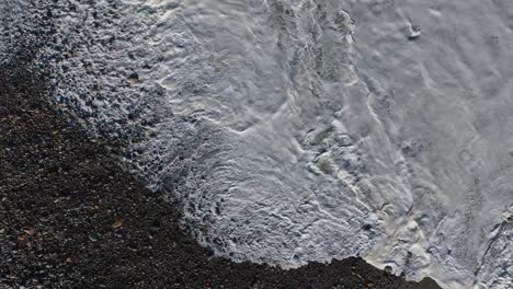 above view of foamy waves over sandy shoreline