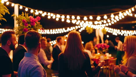outdoor night party with festoon lights and socializing people
