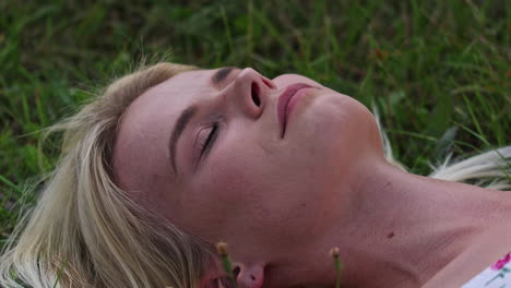 a happy woman laying down in the grass with her face looking up and eyes closed