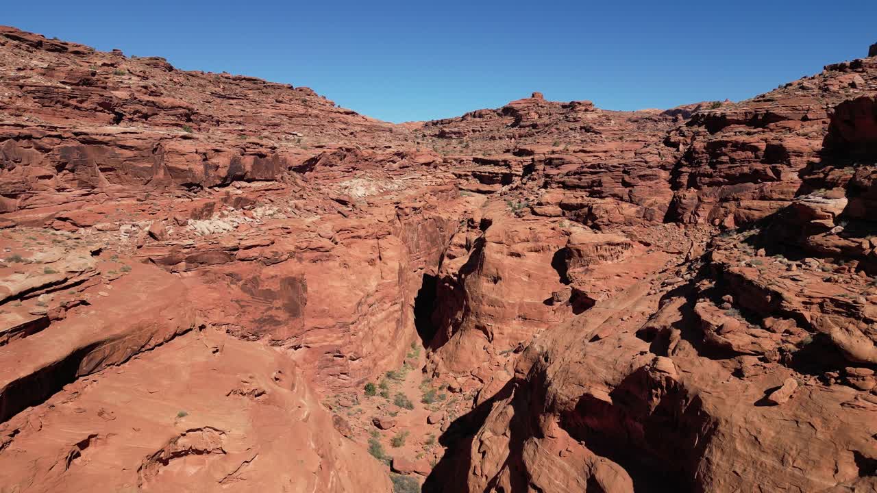 Sorvolo di molteplici strette diramazioni del canyon principale. Pareti di robusta arenaria rossa e terreno ostile sotto la luce solare intensa