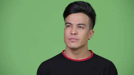 Head shot of young happy multi-ethnic man smiling and thinking