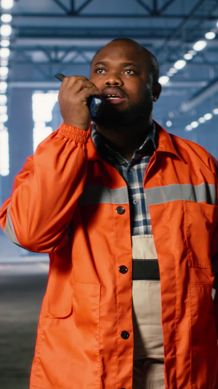 Vertical Video Black operator talks through walkie talkie and monitoring metal fabrication