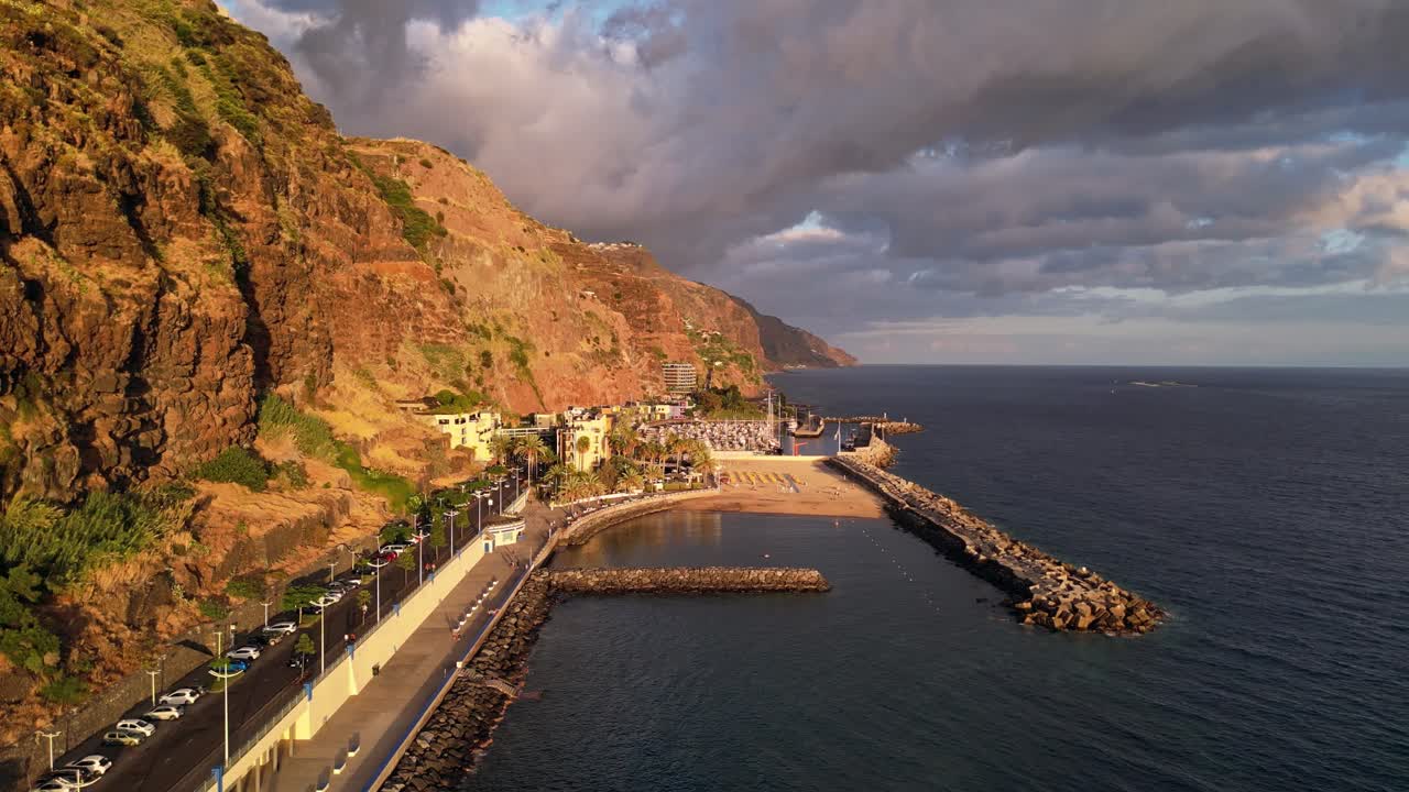 Dramatic cliffs and lush greenery of the coastline of Calheta Madeira, Portugal, at sunset.